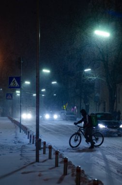 Karlı gece sokağında arabalı bisikletli biri.
