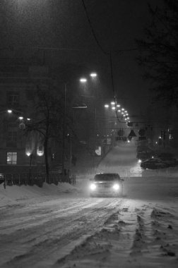 Karlı Kyiv caddesinin siyah beyaz görüntüsü gece aydınlanan arabalarla