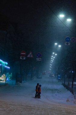 Karlı Kyiv Caddesi 'nden geçen insanlar geceleri aydınlanıyor.
