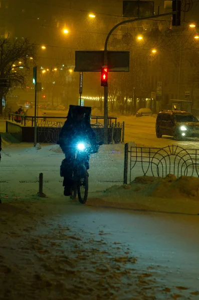 雪の夜の通りを自転車で移動中の配達人のリアビュー — ストック写真