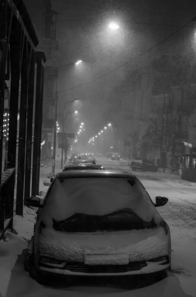 parked car at snowy street at night, black and white