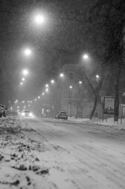Karlı Kyiv caddesinin siyah beyaz görüntüsü gece aydınlanan arabalarla