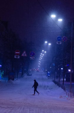 Karlı Kyiv Caddesi 'nden geçen adam gece aydınlandı.