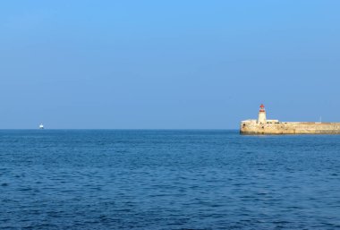 Deniz feneri ve mavi gökyüzü olan deniz manzarası