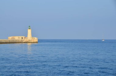Deniz feneri ve mavi gökyüzü olan deniz manzarası