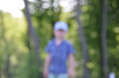 blurred shot of boy standing in greenery
