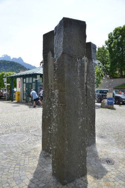 Arka planda insanlar olan taştan bir çeşme burkulmuş su