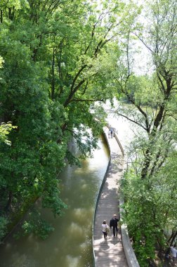 people walking on bridge over river in green park scene