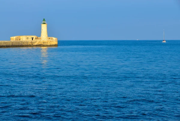 Deniz feneri ve mavi gökyüzü olan deniz manzarası