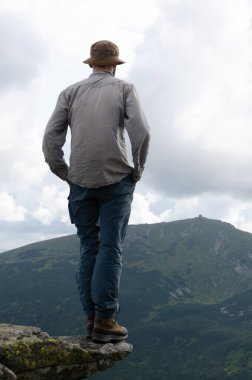 Erkek yürüyüşçü kaya kenarında poz veriyor, dikiz manzarası