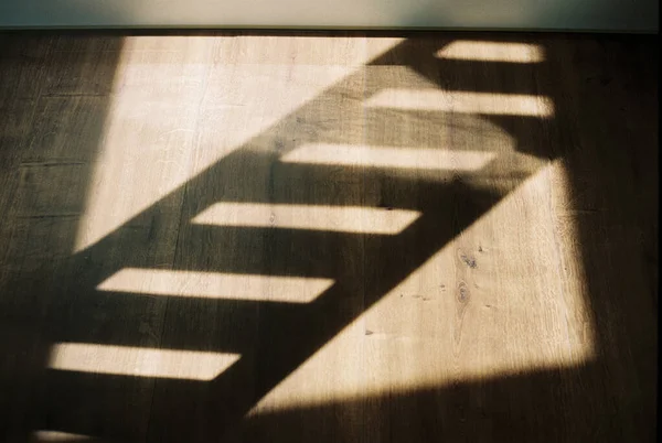 Film photo of shadows of a staircases reflection on wooden floors