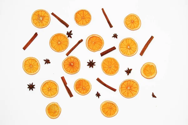 Composition from slices of dried oranges and cinnamon sticks on a white background.