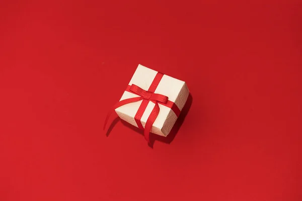 Caja de regalo blanca con cinta roja sobre fondo rojo. Concepto de Día de San Valentín, copiar espacio y maqueta — Foto de Stock