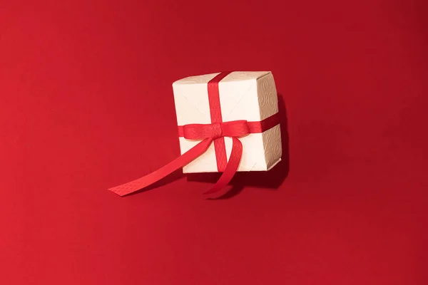 Caja de regalo blanca con cinta roja sobre fondo rojo. Concepto de Día de San Valentín, copiar espacio y maqueta — Foto de Stock