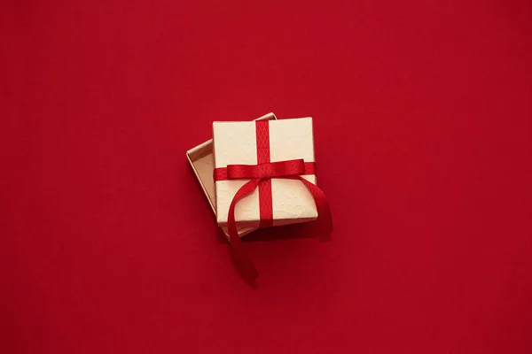 Caja de regalo blanca con cinta roja sobre fondo rojo. Concepto de Día de San Valentín, copiar espacio y maqueta — Foto de Stock