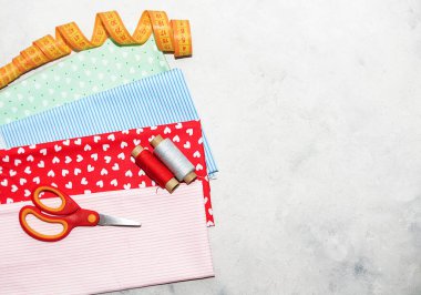Beyaz arka planda dikiş aletleri ve çok renkli kumaş. Dikiş, dikiş, nakış ve tiolori konsepti. Çok renkli iplikler, iğneler, kumaş, makas ve dikiş dikmek. 