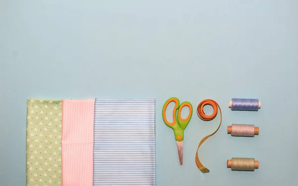 Sewing tools and multi color fabric on a white background. Concept for needlework, stiching, embroidery and tiolori. Sewing multicolored threads, needles, fabric, scissors and sewing centimeter.