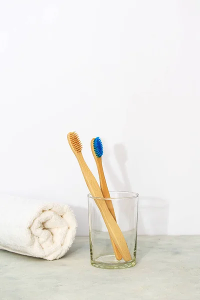Eco bamboo tooth brushes in a glass and white towel in white background. Concept of zero waste and eco-friendly products