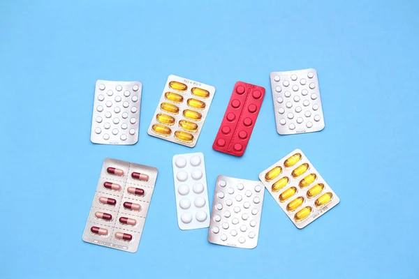 Mavi arka planda çeşitli renkli haplar ve vitaminler. Sağlık hizmeti kavramı
