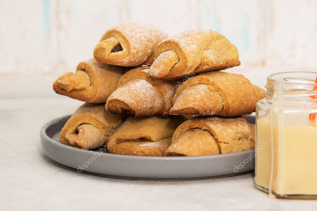 Homemade pastry. The rugelach with apple jam and condensed milk in a gray plate on a table. Traditional Jewish holiday cookie, Bagels, Croissants, Still life photography with cookies.