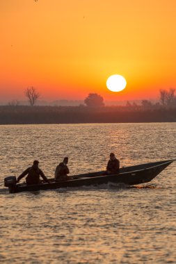 Yükselen güneş ışınlarının içinde yüzen tekne