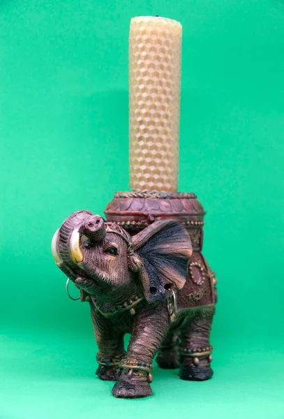 Figurine of an Indian elephant on a green background close-up. Candlestick in the shape of an Indian elephant.