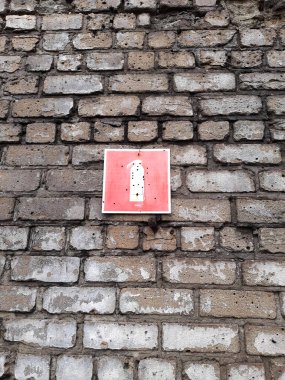 Tuğla duvarda yangın söndürücü işareti ve yakın plan kurşun delikleri var..