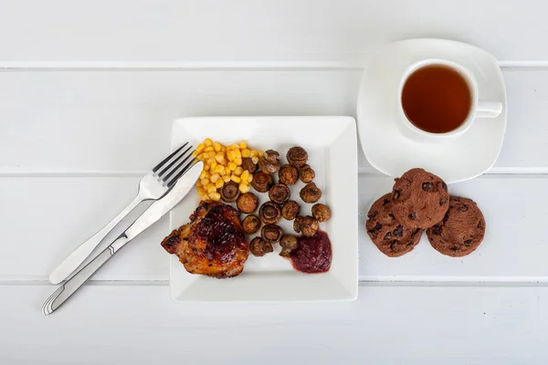 Assiette de nourriture et une tasse de thé sur un fond de bois blanc — Photo