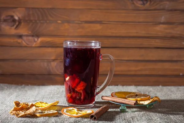 Mulled wine in a glass with spices, ginger, lemon, cinnamon and fruit on a wooden background — Stock Photo, Image