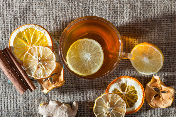 Ginger tea with spices, honey, cinnamon, lemon and dried fruit on a linen background