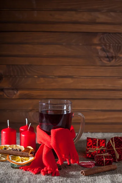 Vino caliente en una copa con especias, jengibre, limón, canela y fruta sobre un fondo de madera — Foto de Stock