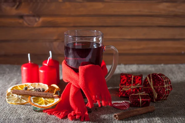 Vinho amontoado em um copo com especiarias, gengibre, limão, canela e frutas em um fundo de madeira — Fotografia de Stock