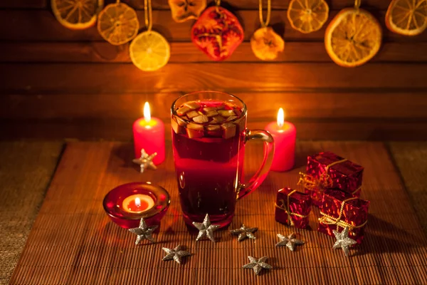 Glass of mulled wine and Christmas decorations, candles, gifts on linen background — Stock Photo, Image