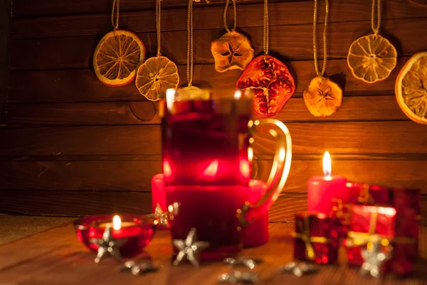 Glass of mulled wine and Christmas decorations, candles, gifts on linen background — Stock Photo, Image