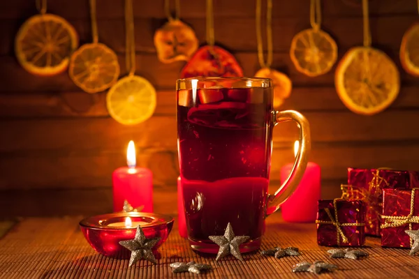 Glas glühwein en kerstversiering, kaarsen, geschenken op linnen achtergrond Stockfoto
