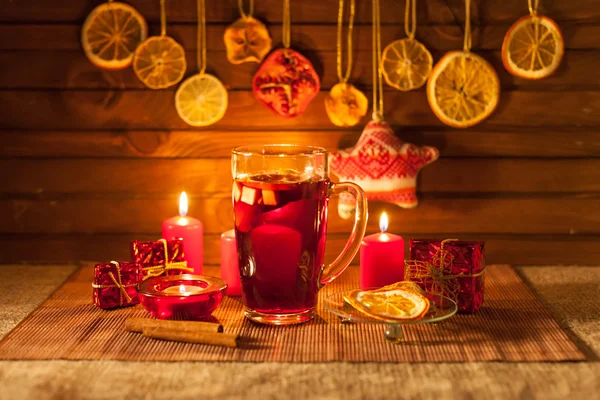 Copa de vino caliente y decoraciones navideñas, velas, regalos sobre fondo de lino — Foto de Stock
