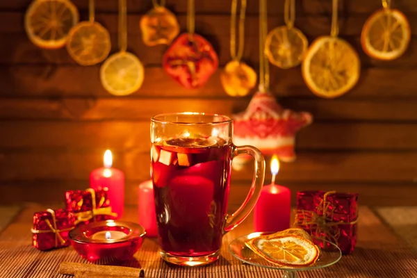 Copa de vino caliente y decoraciones navideñas, velas, regalos sobre fondo de lino — Foto de Stock