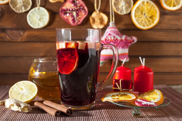 Glass of mulled wine and Christmas decorations, candles, gifts on linen background — Stock Photo, Image