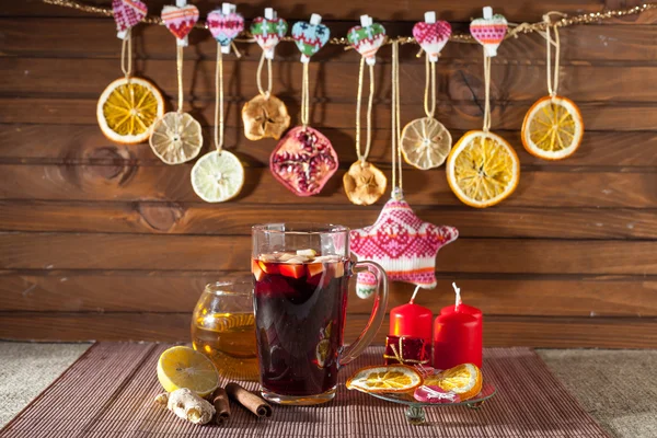 Glass of mulled wine and Christmas decorations, candles, gifts on linen background — Stock Photo, Image