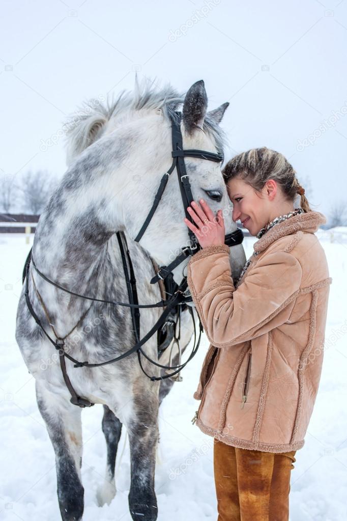 a girl with a horse in the winter on snow