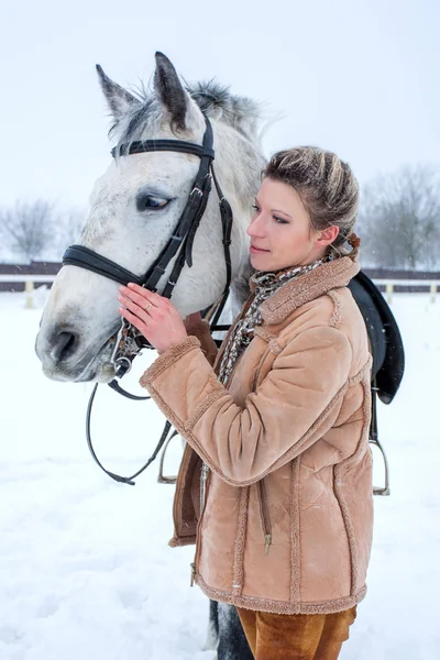 En tjej med en häst på vintern i snön Stockbild