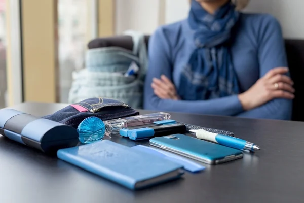 Le contenu du sac à main pour femme sur la table en bleu Image En Vente
