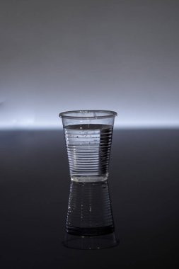 Gri bir arkaplanda bir bardak su.