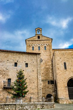 Katedral yakınlarındaki ortaçağ köyü Anagni 'de renkli toplar, çiçekler ve çelenkler, kırmızı yıldızlar ve ışıklarla süslenmiş büyük bir Noel ağacı. Roma, Lazio, İtalya.