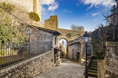 12 Şubat 2021 - Castel San Pietro Romano, Lazio, Roma, Palestrina - Ortaçağ köyüne bir bakış, evler arasındaki kaldırımlı ara sokak. Kalenin taş köprüsünün oluşturduğu kemer..
