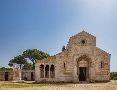 10 Ağustos 2021 - Santa Maria Manastırı a Cerrate, Puglia, Salento, Lecce - Antik Roma Kilisesi, FAI 'nin mirası. Ön cephe, kuyu ve sütunları olan kapıcı. Yazın mavi gökyüzü.