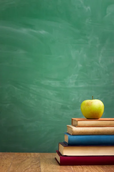 Libros escolares con manzana en el escritorio —  Fotos de Stock