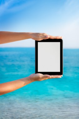 Tablet PC ile deniz kıyısında arka planda 