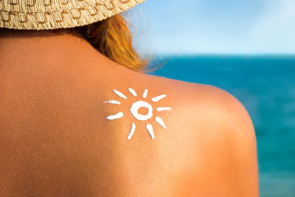 Woman with suntan lotion at the beach in form of the sun — Stock Photo, Image