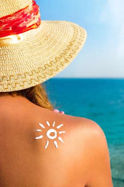 Schöne Mädchen mit Sonnencreme auf dem Rücken über Meer backgro — Stockfoto